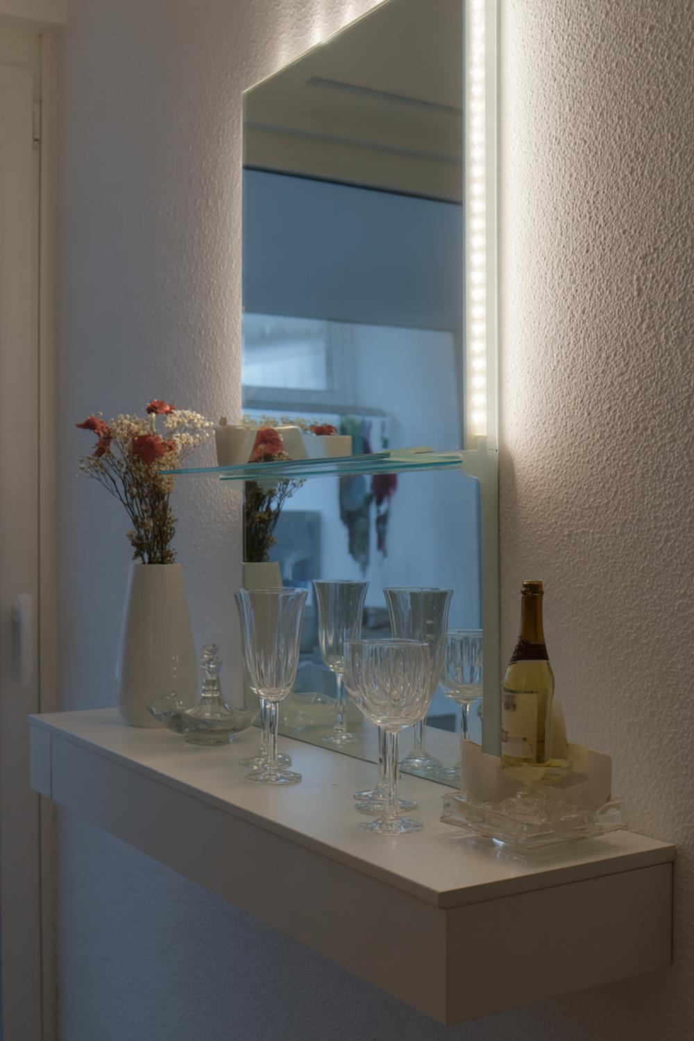 22. Spiegelwand mit LED-Lichterkette und Glasglocken auf der Konsole