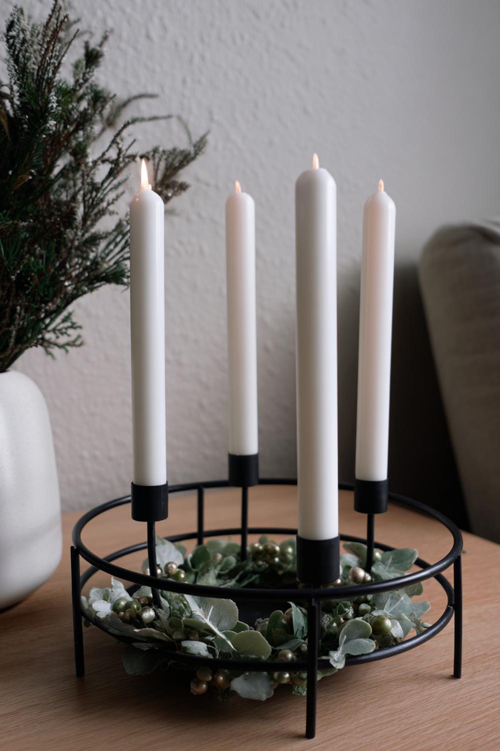 2. Weihnachtsdeko minimalistisch Wohnung: Schwarzer Metallring als Kerzenkranz mit vier weißen Stabkerzen