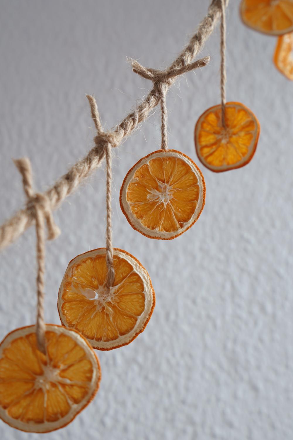 9. Weihnachtsdeko minimalistisch Wohnung: Getrocknete Orangenscheiben an Hanfschnur vor hellem Putz